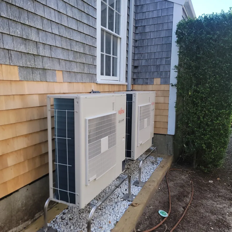 Two Fujitsu Airstage condenser units installed beside a shingled home